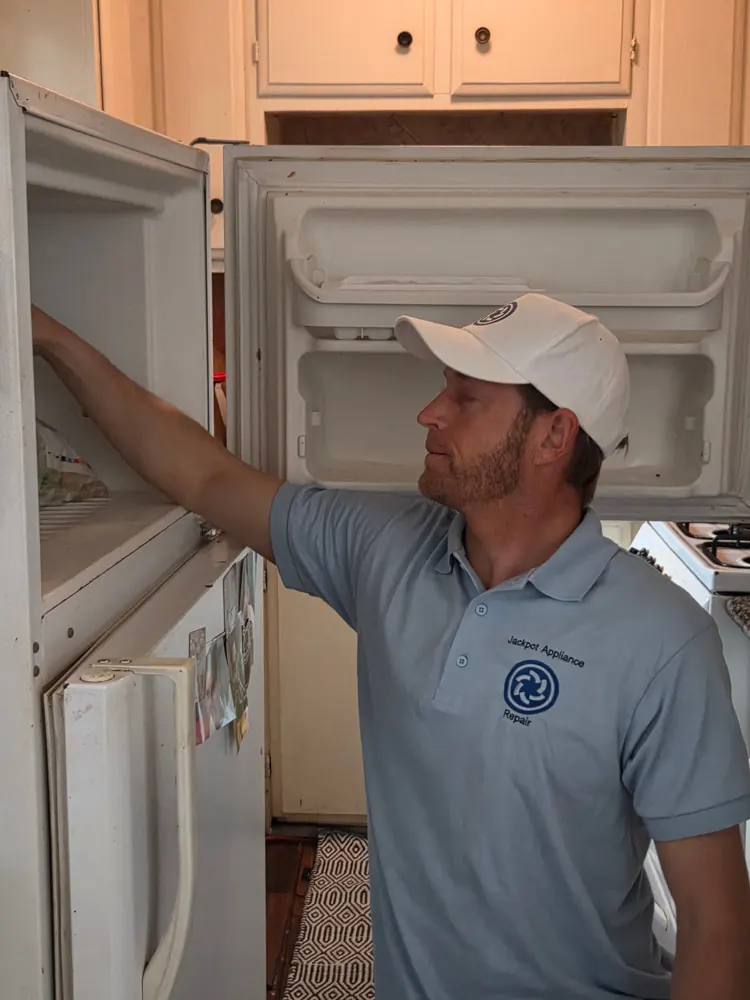 Technician diagnosing a top-freezer refrigerator in a Las Vegas home